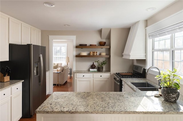 kitchen featuring stainless steel appliances, light stone counters, a sink, and white cabinets