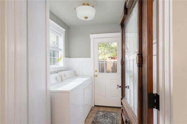 clothes washing area with laundry area, a healthy amount of sunlight, wainscoting, and washing machine and clothes dryer