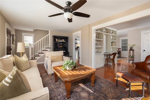 living room with baseboards, stairs, a ceiling fan, and wood finished floors