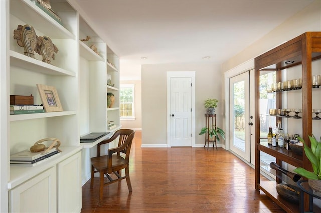 home office with dark wood-style floors, built in study area, built in features, and baseboards