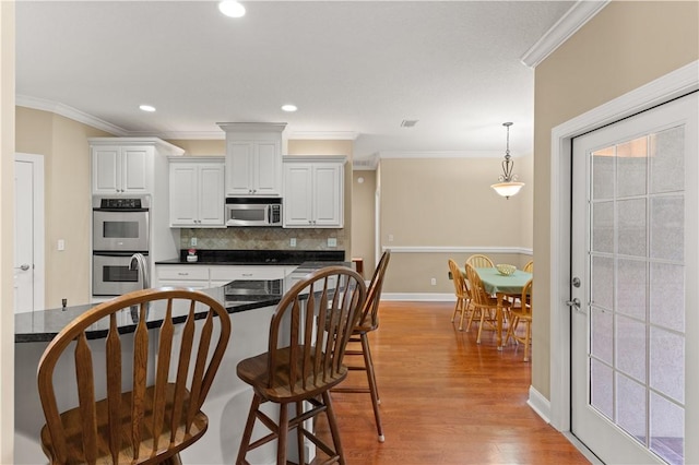 kitchen featuring white cabinetry, ornamental molding, and appliances with stainless steel finishes