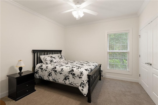 bedroom with ceiling fan, light colored carpet, crown molding, and a closet