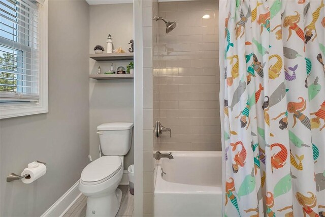 full bathroom with shower / bath combination with curtain, toilet, and baseboards