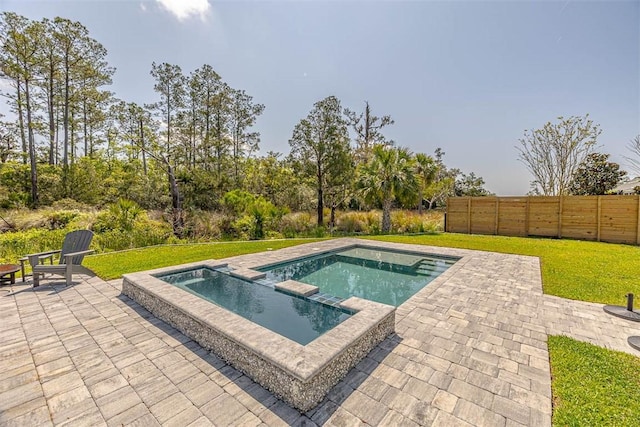 view of swimming pool featuring fence, a pool with connected hot tub, a patio, and a yard