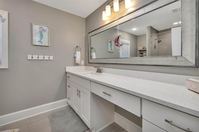 full bathroom featuring baseboards, visible vents, tiled shower, and vanity
