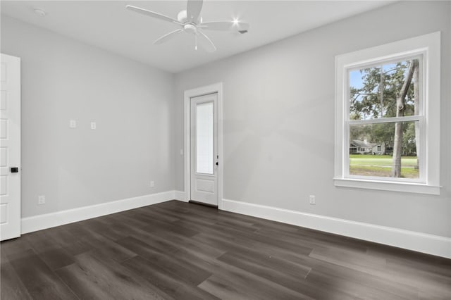 empty room with dark wood-type flooring, ceiling fan, and a healthy amount of sunlight