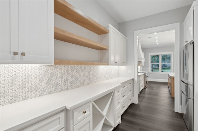 kitchen with white cabinets, dark hardwood / wood-style floors, appliances with stainless steel finishes, and tasteful backsplash