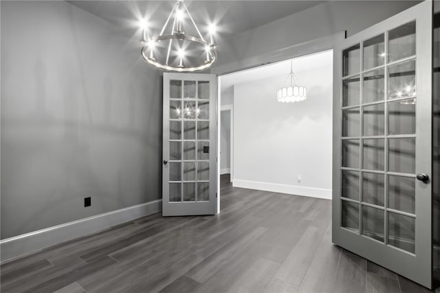 unfurnished dining area featuring a chandelier and wood-type flooring