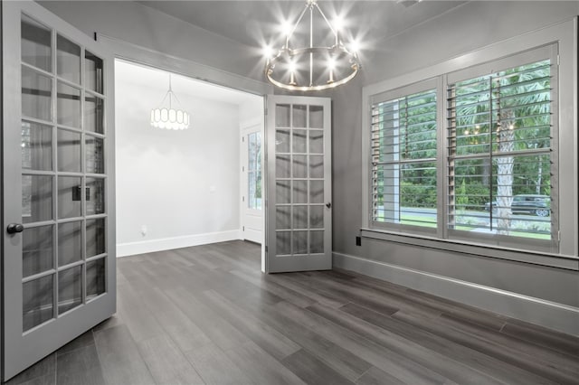 unfurnished room featuring a notable chandelier, dark hardwood / wood-style floors, and french doors