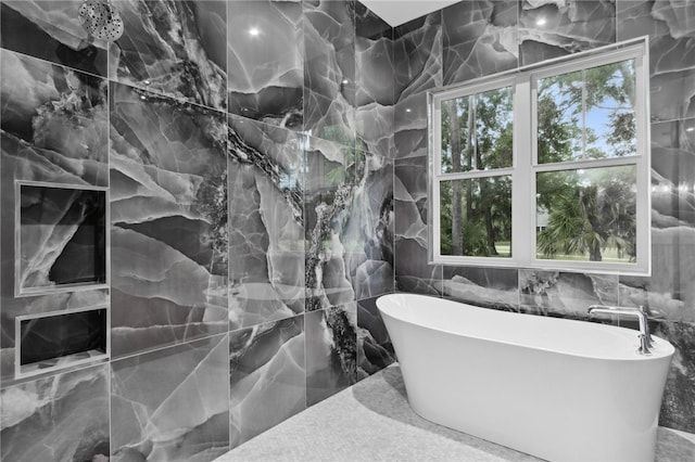 bathroom featuring a tub, a healthy amount of sunlight, and tile walls