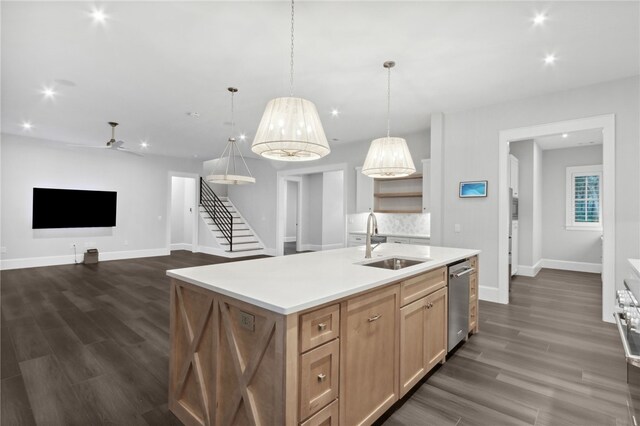 kitchen featuring dishwasher, sink, hanging light fixtures, ceiling fan, and an island with sink