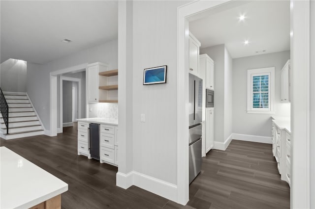 kitchen featuring decorative backsplash, stainless steel appliances, beverage cooler, white cabinets, and dark hardwood / wood-style floors