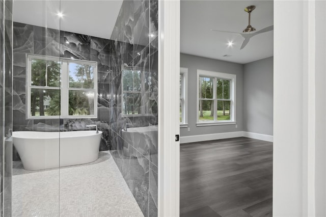 bathroom featuring ceiling fan, a washtub, tile walls, and hardwood / wood-style flooring