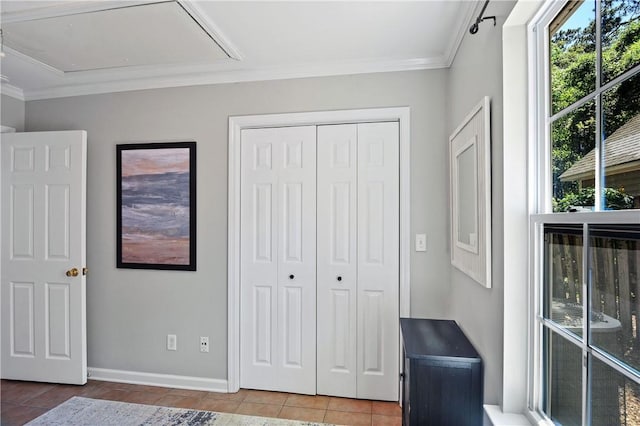 bedroom featuring crown molding, a closet, attic access, baseboards, and tile patterned flooring