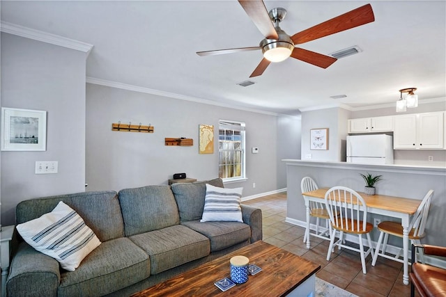 living room with tile patterned floors, visible vents, baseboards, a ceiling fan, and crown molding