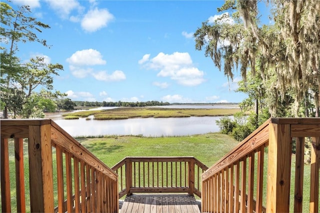 wooden deck featuring a water view and a lawn