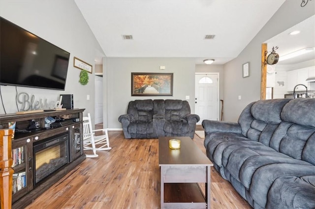 living room with light wood-type flooring and lofted ceiling