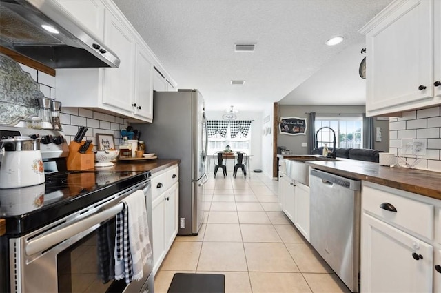 kitchen with white cabinetry, decorative backsplash, extractor fan, and appliances with stainless steel finishes