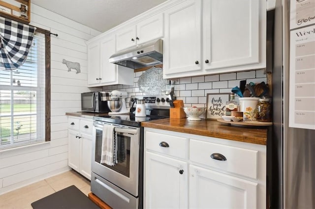 kitchen with electric range, light tile patterned floors, wooden counters, wooden walls, and white cabinets