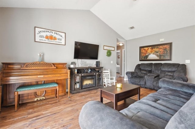 living room featuring a fireplace, light hardwood / wood-style flooring, and vaulted ceiling