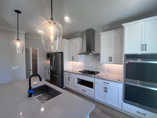 35 Fairwinds Dr, Waverly, GA 31565 - kitchen with appliances with stainless steel finishes, wall chimney exhaust hood, a sink, white cabinetry, and pendant lighting