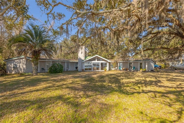 back of property with a yard and a sunroom