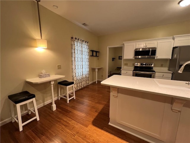 kitchen featuring white cabinetry, stainless steel appliances, and a kitchen breakfast bar