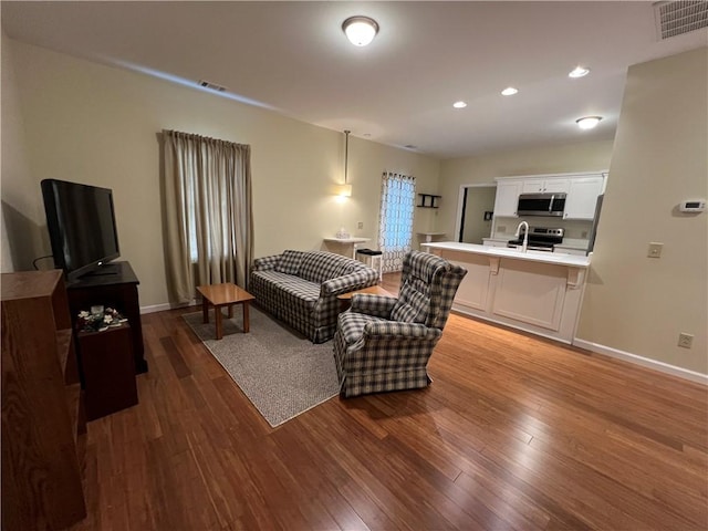 living area with visible vents, baseboards, and wood finished floors