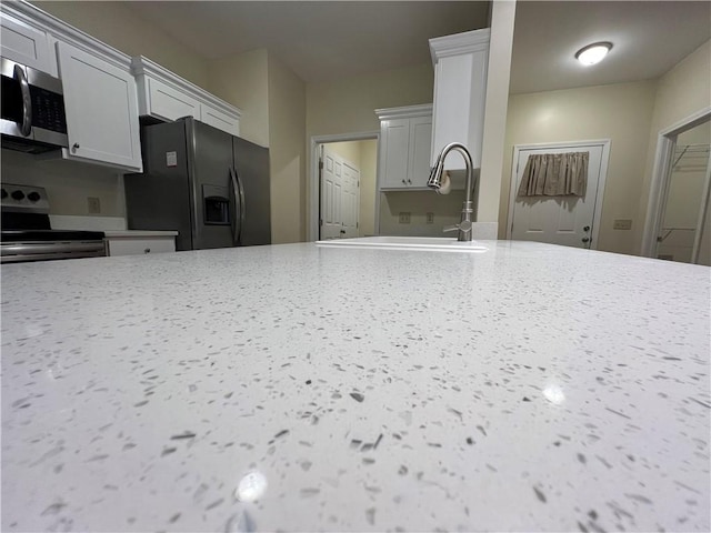 kitchen featuring a sink, light stone counters, appliances with stainless steel finishes, and gray cabinets