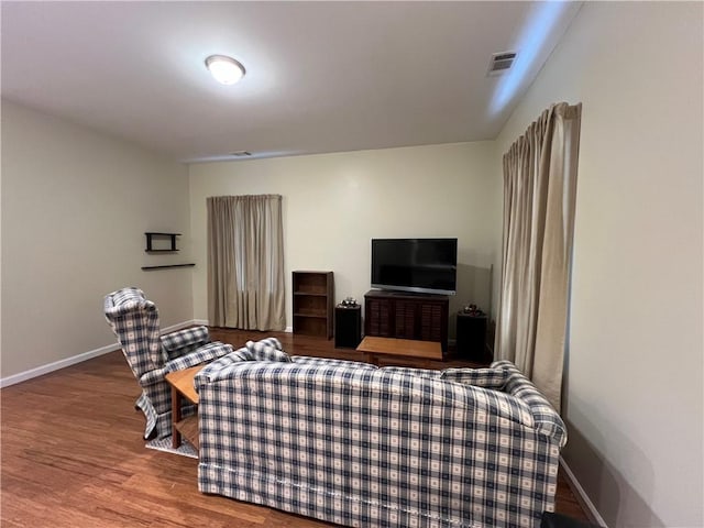 living room featuring wood finished floors, visible vents, and baseboards