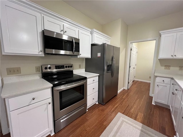 kitchen with white cabinets, appliances with stainless steel finishes, light countertops, and dark wood-style flooring