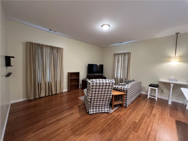 living area with visible vents, baseboards, and wood finished floors