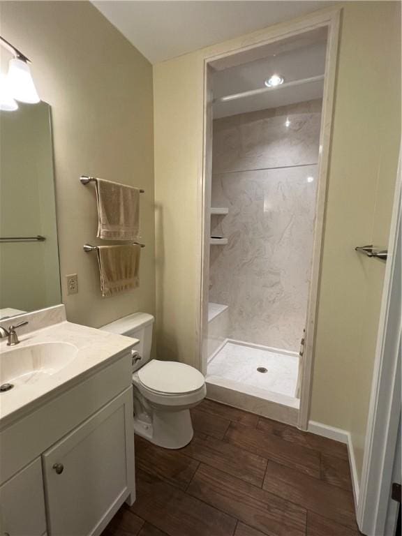 bathroom with toilet, a stall shower, vanity, and wood finished floors