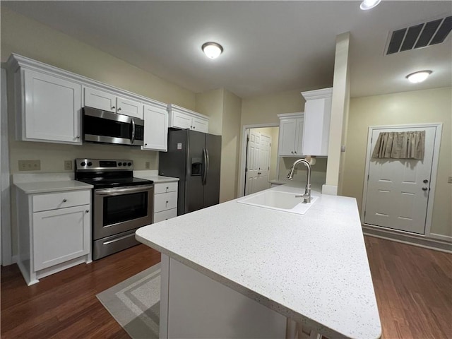 kitchen featuring visible vents, a sink, dark wood-style floors, appliances with stainless steel finishes, and light countertops