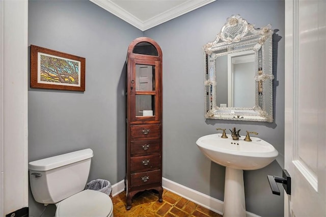 bathroom featuring brick floor, toilet, crown molding, and baseboards