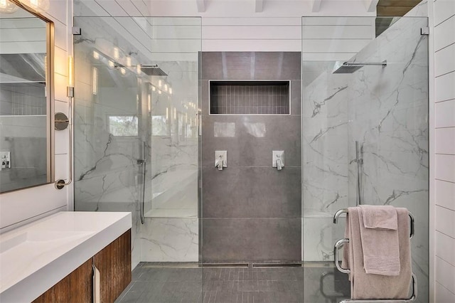 full bathroom with a marble finish shower and vanity