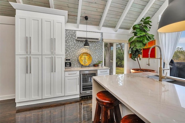 kitchen with vaulted ceiling with beams, wine cooler, light stone counters, hanging light fixtures, and decorative backsplash