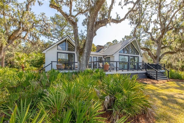 rear view of property featuring a chimney and a wooden deck