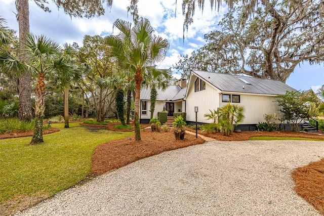 view of side of home featuring metal roof, a yard, and gravel driveway