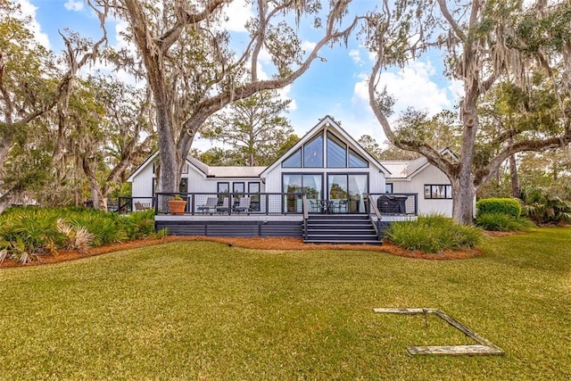 back of house featuring a lawn and a wooden deck