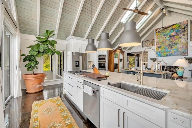 kitchen with light stone counters, stainless steel appliances, a sink, white cabinetry, and dark wood-style floors