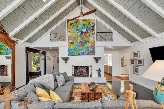 living area with baseboards, a fireplace, beam ceiling, and wood finished floors