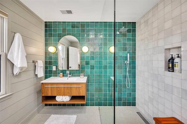 full bathroom featuring visible vents, tile walls, vanity, and a walk in shower