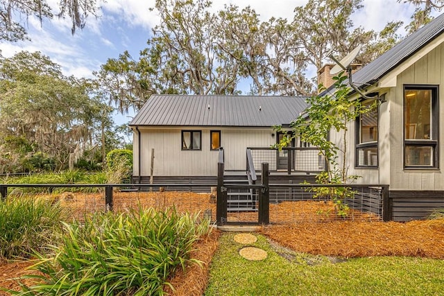 view of front of property with metal roof, a chimney, and fence