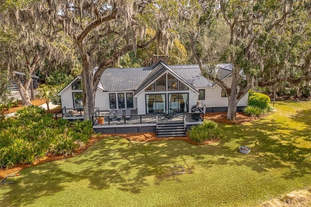 rear view of property with a wooden deck, metal roof, and a yard