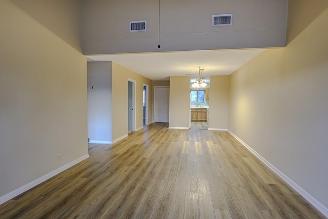 interior space featuring an inviting chandelier, wood finished floors, visible vents, and baseboards