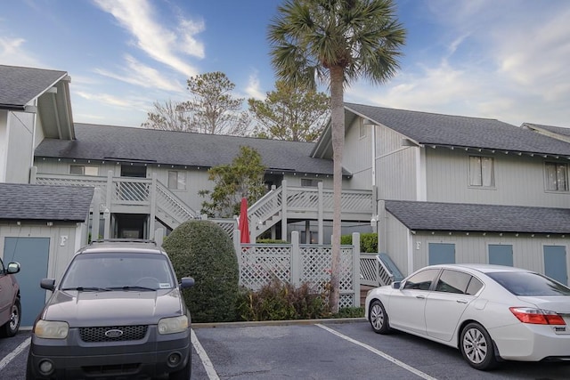 view of front of house featuring uncovered parking, stairs, and a shingled roof