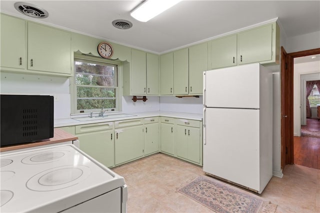 kitchen featuring sink, green cabinets, and white appliances