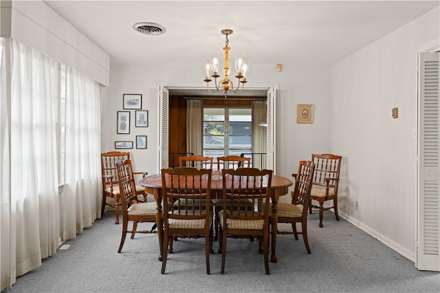 dining space with carpet floors and a chandelier