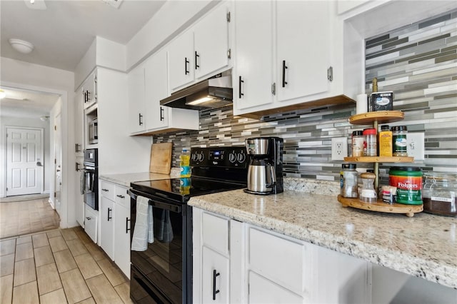 501 W Hall St, Saint Marys, GA 31558 - kitchen featuring under cabinet range hood, wood tiled floor, black appliances, backsplash, and white cabinets